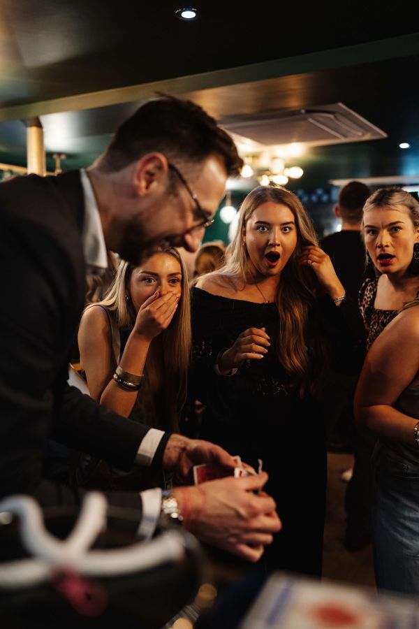 Party magician performing close-up magic at an adult party
