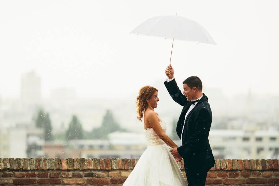 Bride and groom under an umbrella on a rainy wedding day