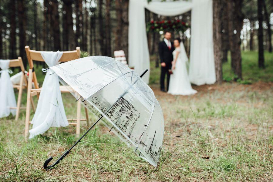 Wedding couple under umbrellas in the rain