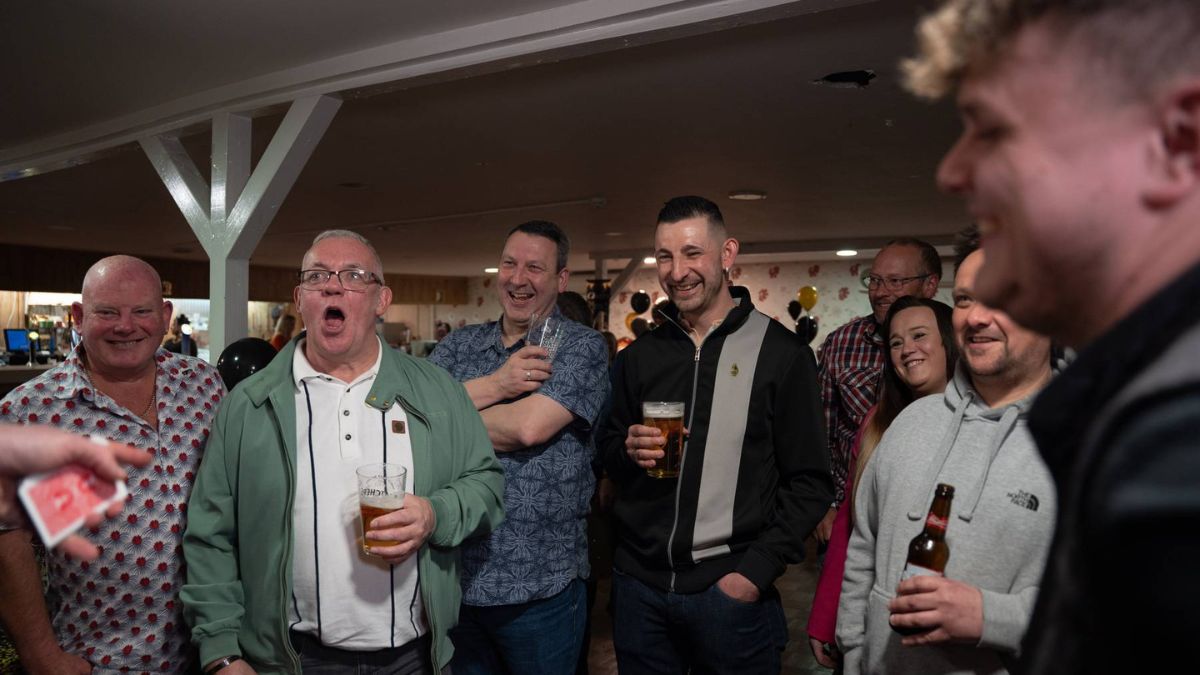 Guests reacting to a card trick at an evening gathering