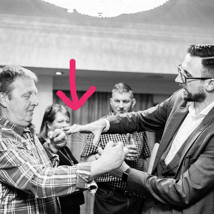 Magician positioning the guest's hands for the elastic band trick